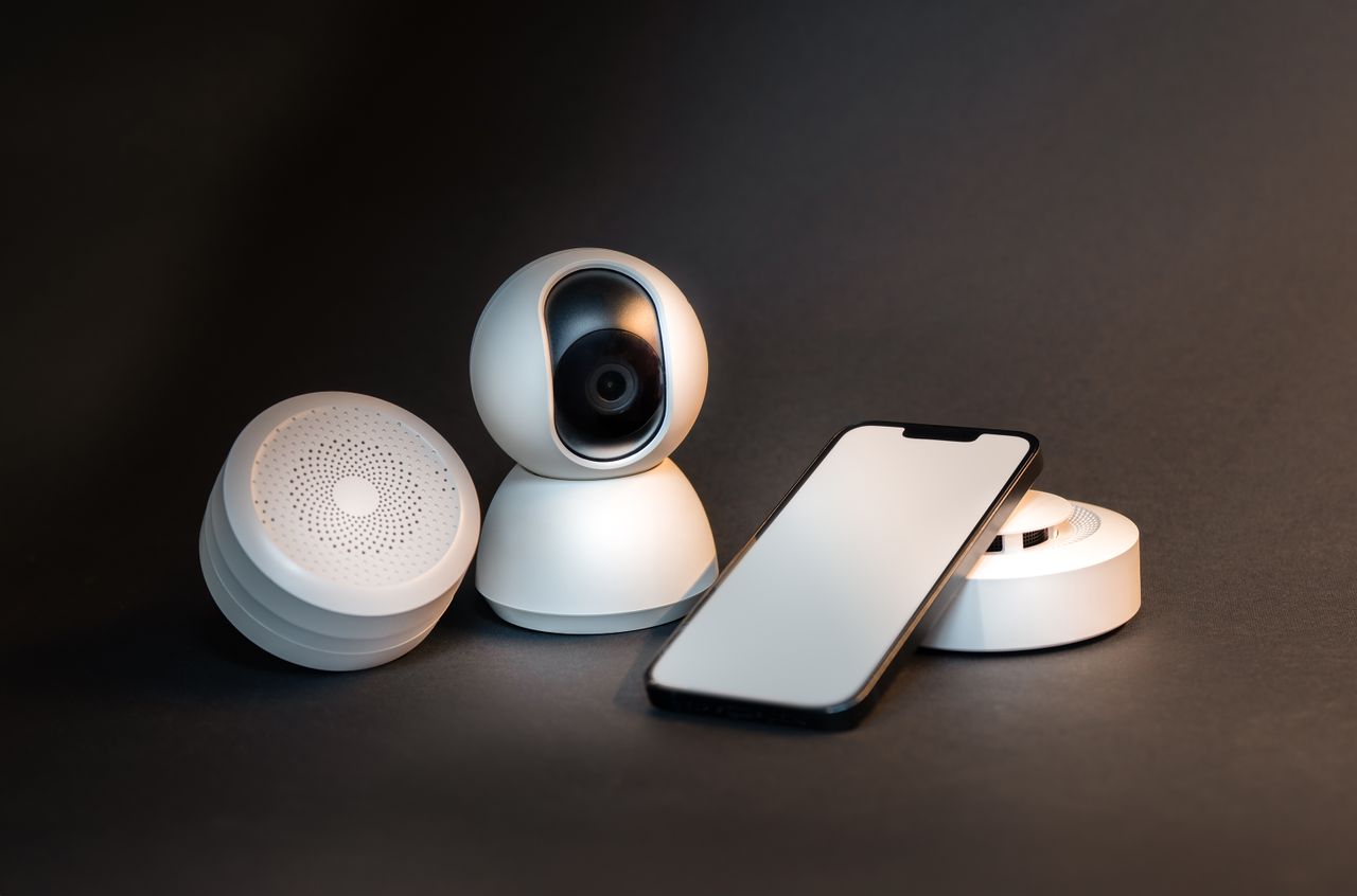 why-choose-us A sleek smartphone with modern smart home devices on a minimalist gray background.